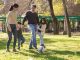 A family plays soccer together in a sunny park, enjoying quality time outdoors.
